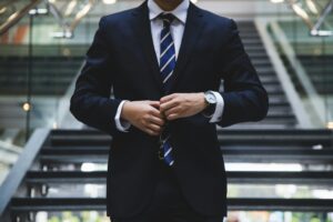 A man in a suit buttoning his jacket.