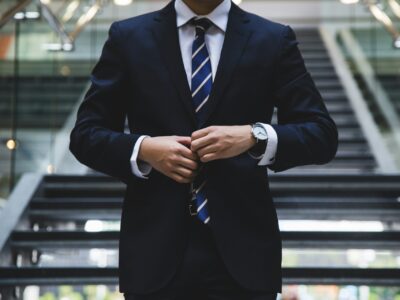 A man in a suit buttoning his jacket.