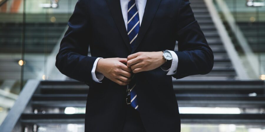 A man in a suit buttoning his jacket.