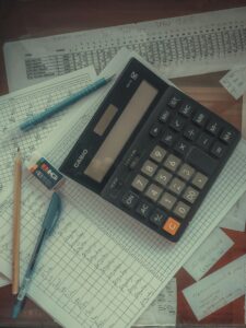 A digital calculator resting on paper accounting ledgers.