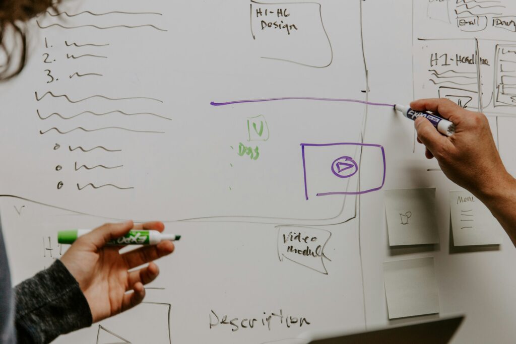 Two professionals working out a strategy on a whiteboard.