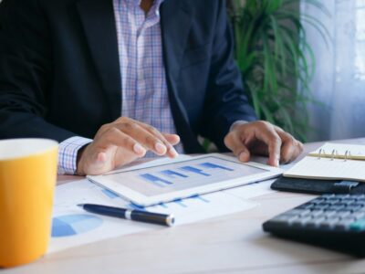 A man in professional clothing working with a tablet and papers.